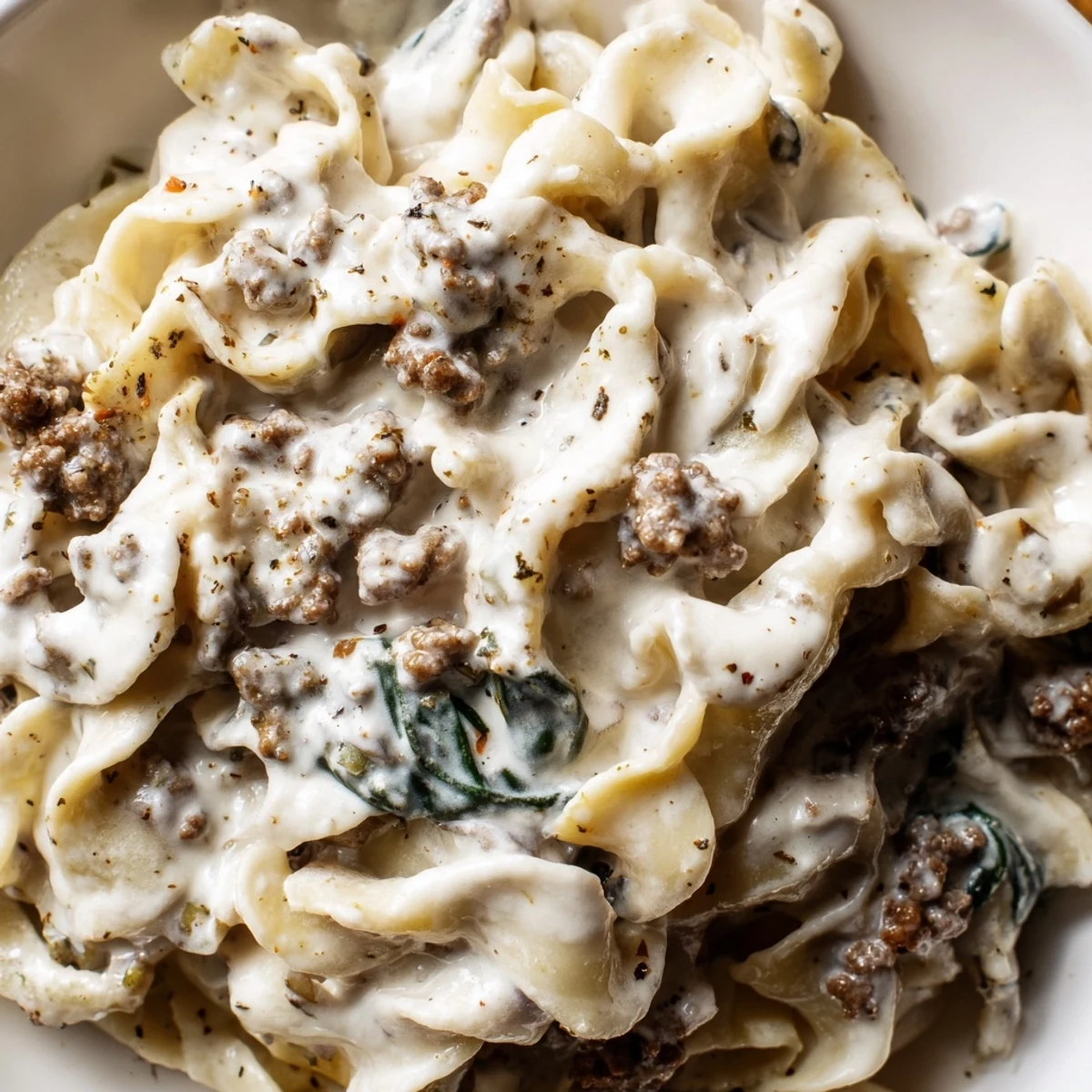Creamy high protein beef pasta topped with Parmesan in a rustic white bowl