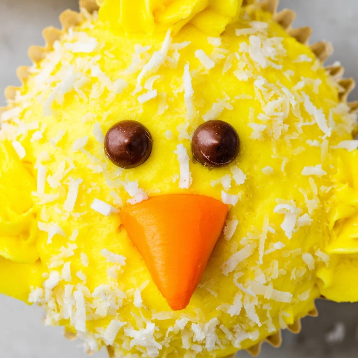 Adorable Easter Chick Cupcakes with fluffy yellow frosting and chocolate chip eyes on a spring dessert tray