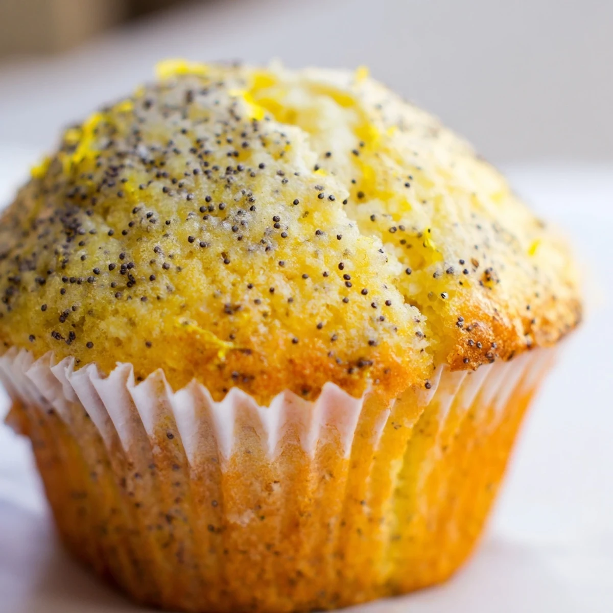 Moist lemon poppy seed muffins studded with tiny black seeds served on a rustic white plate
