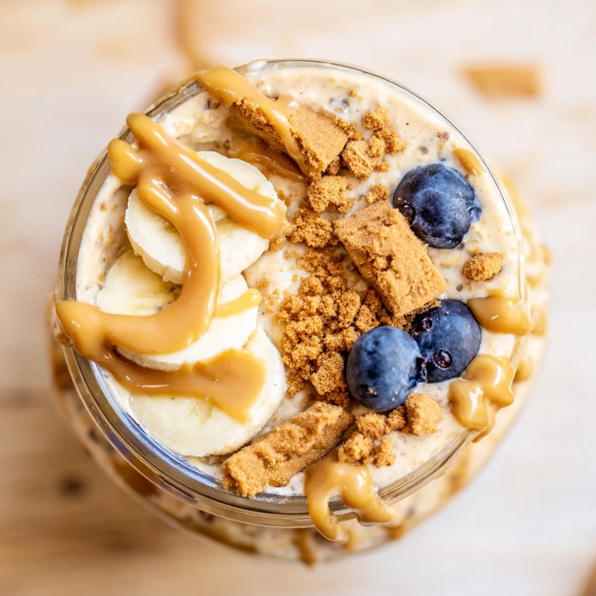 Quick Biscoff Overnight Oats swirled with caramel-colored spread and fresh banana slices