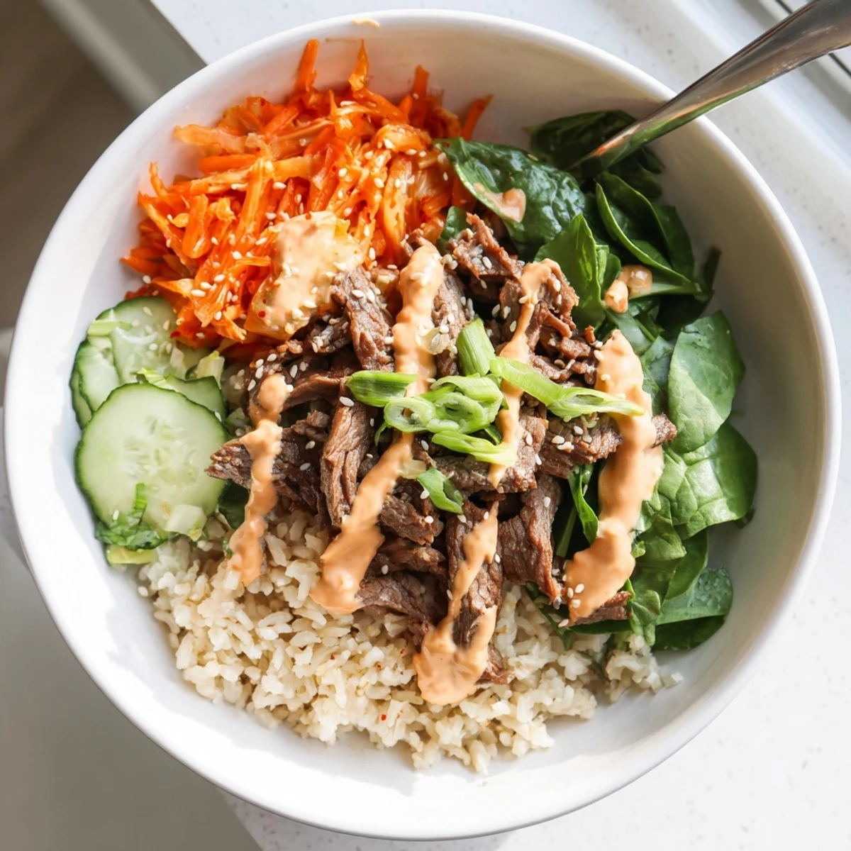 Korean BBQ steak rice bowls drizzled with creamy spicy sauce and crisp veggies