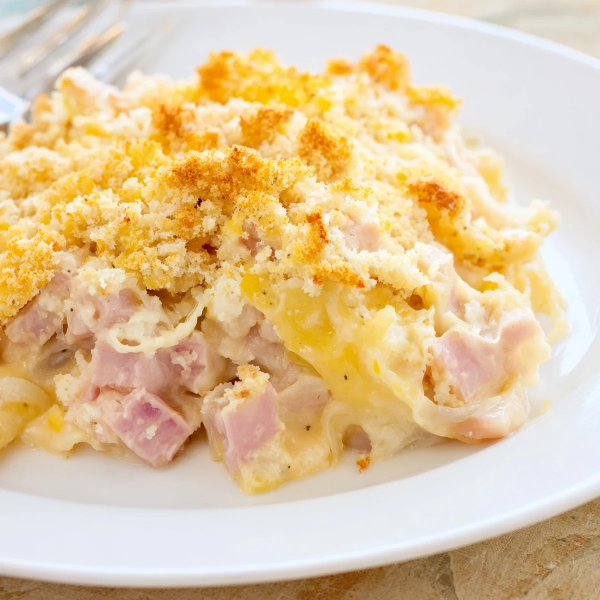 Slice of Chicken Cordon Bleu Casserole on plate, golden edges and gooey cheese