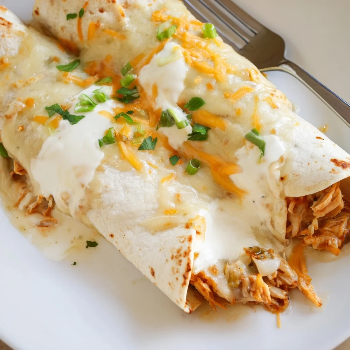 Hot White Rotisserie Chicken Enchiladas bubbling with creamy white sauce, melted cheese