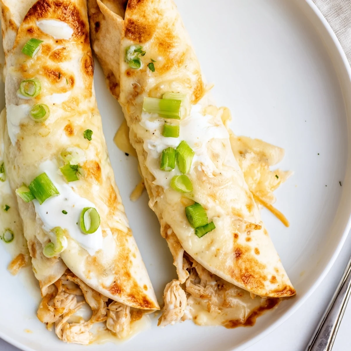 Creamy White Rotisserie Chicken Enchiladas rolled in warm tortillas, ready to plate