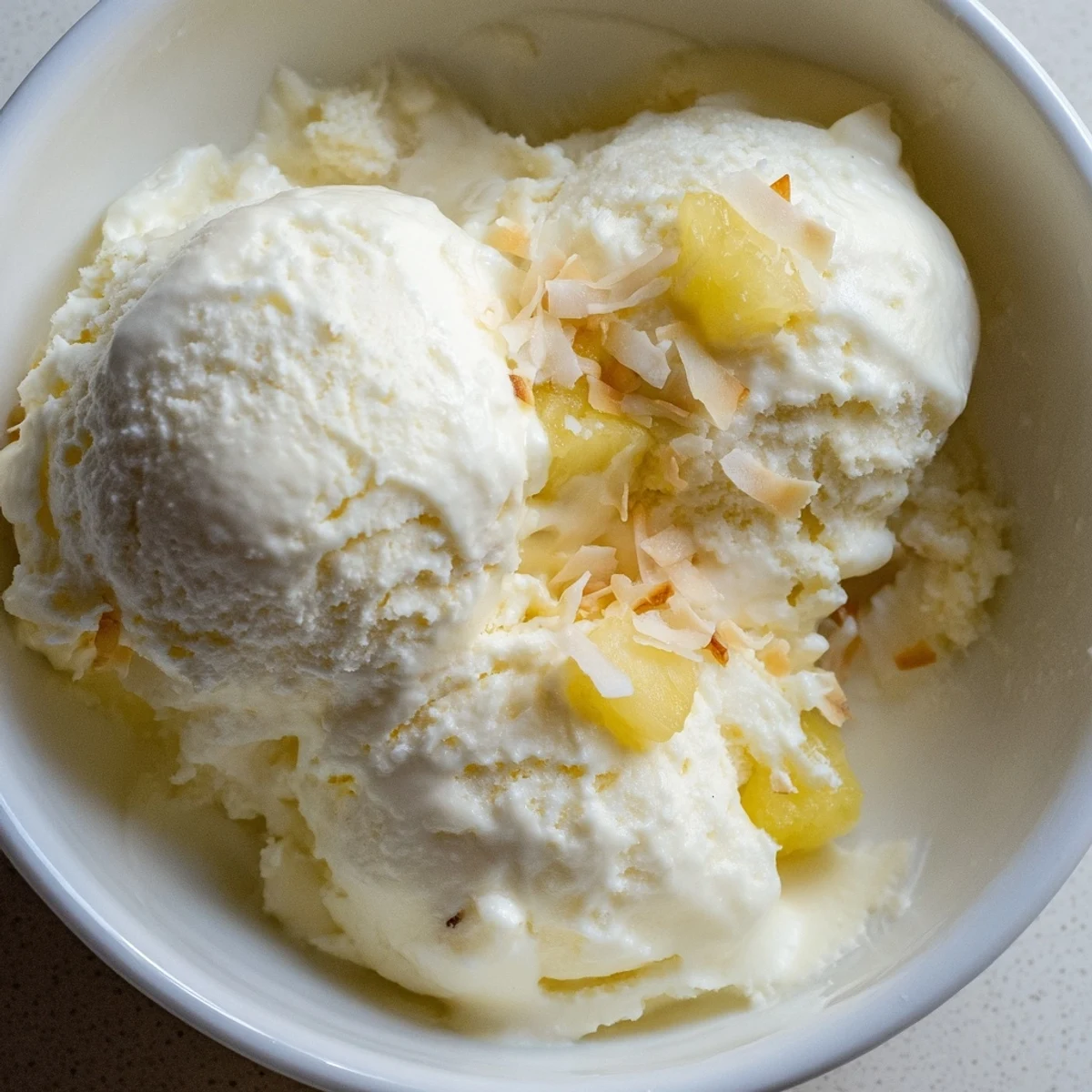 Homemade Creamy Pineapple Ice Cream shown churning, ready for freezer.