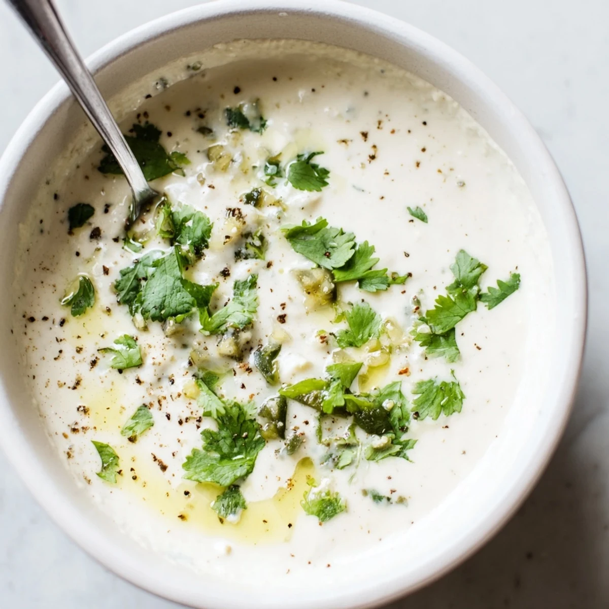 Creamy Mexican white sauce drizzled over crispy tacos with fresh cilantro garnish