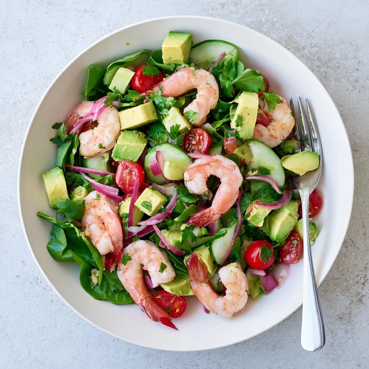 Colorful shrimp avocado salad recipe plated with succulent seafood, creamy avocado slices, red onion, and refreshing vegetables topped with citrus vinaigrette