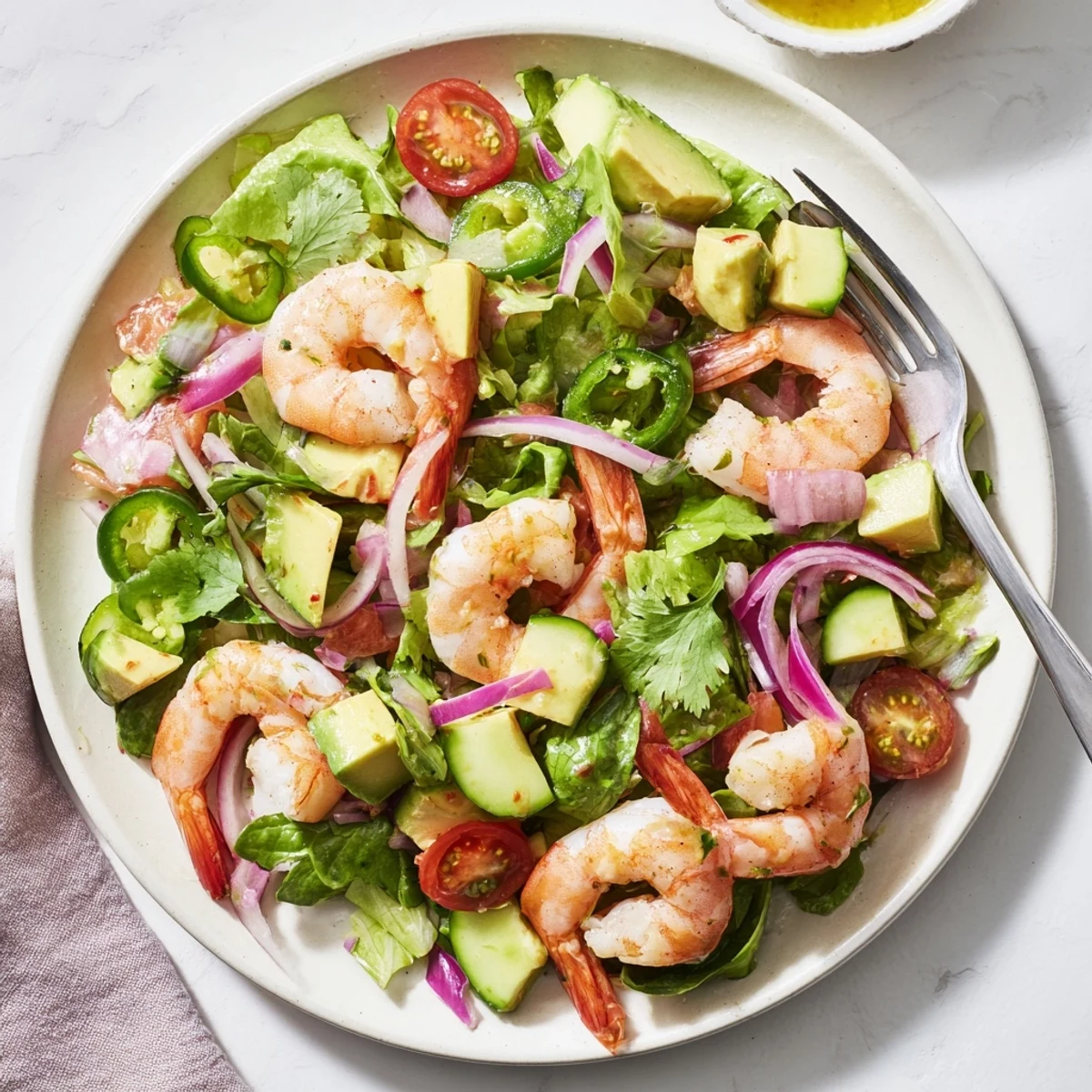 Fresh shrimp avocado salad recipe with pink shrimp, diced avocado, cherry tomatoes, and crisp cucumber on mixed greens drizzled with zesty lime dressing
