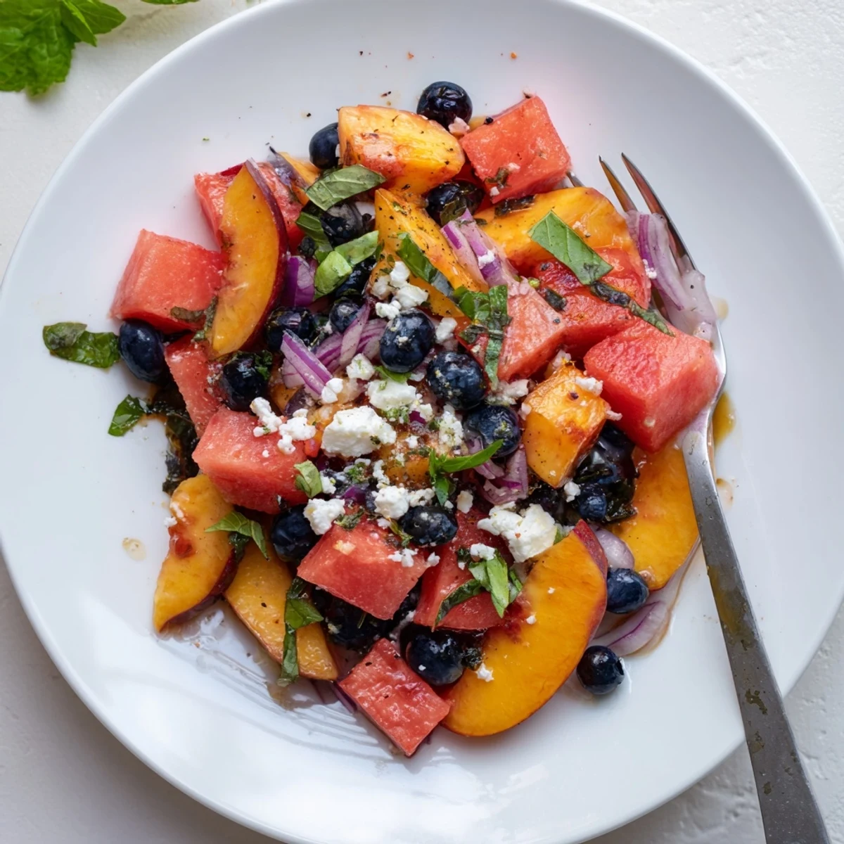 A vibrant Peach Watermelon Salad With Feta topped with mint and lime.