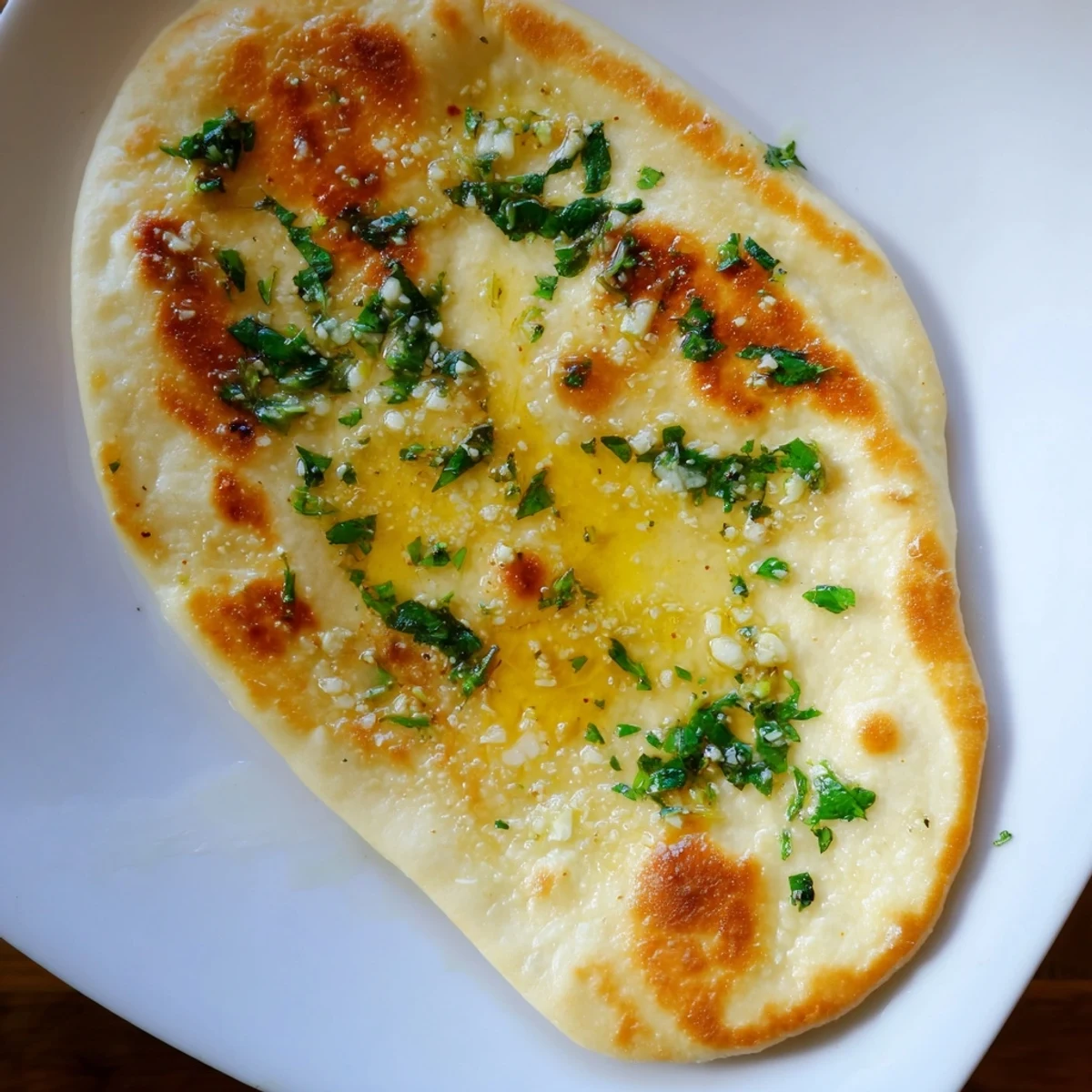 Golden brown sourdough discard soft naan brushed with melted butter and fresh herbs
