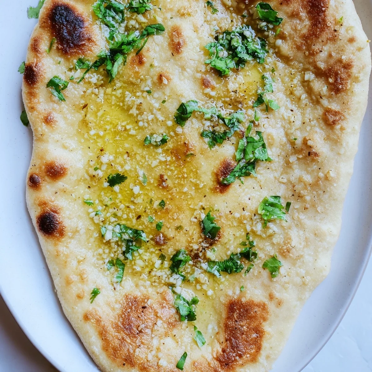 Pillowy Indian-style sourdough discard soft naan with charred bubbles and golden spots