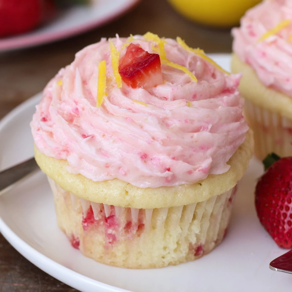 Strawberry Lemonade Cupcakes topped with pink buttercream and lemon zest, picnic-ready.