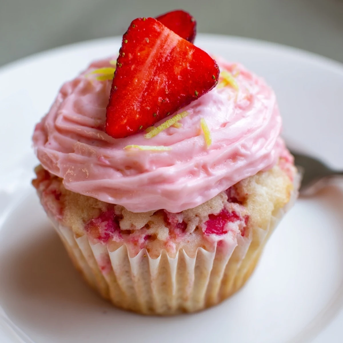 Fresh-baked Strawberry Lemonade Cupcakes cooling on wire rack, garnished with strawberries.
