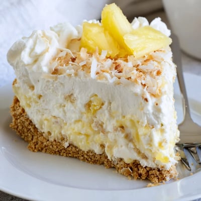 Chilled no bake pineapple coconut cream cake topped with golden toasted coconut flakes and pineapple garnish